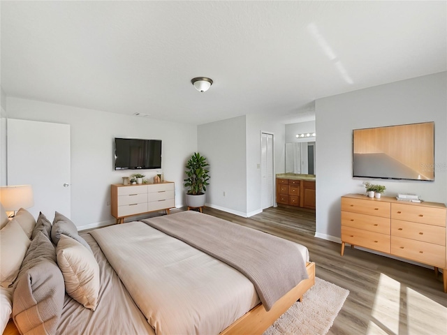 bedroom featuring ensuite bathroom, wood finished floors, and baseboards