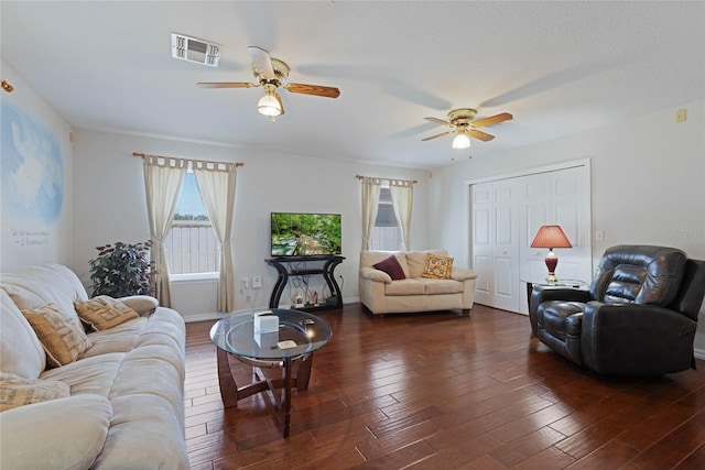 living area featuring dark wood-style floors, visible vents, baseboards, and a ceiling fan