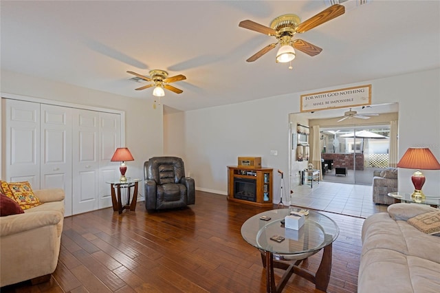 living area featuring visible vents, baseboards, ceiling fan, wood finished floors, and a glass covered fireplace