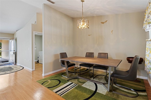 dining area featuring baseboards, wood finished floors, a chandelier, and washer / clothes dryer