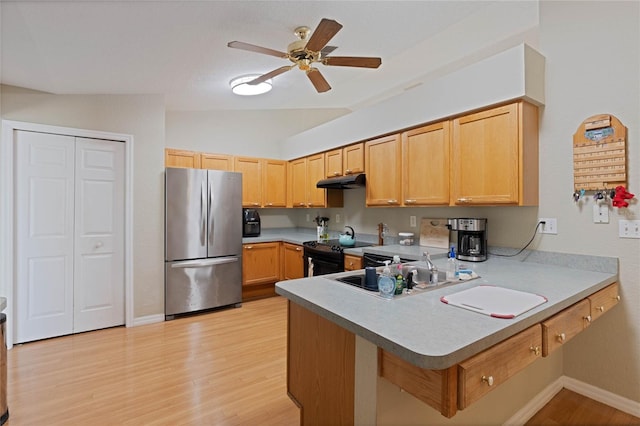 kitchen featuring black / electric stove, a peninsula, freestanding refrigerator, ceiling fan, and under cabinet range hood