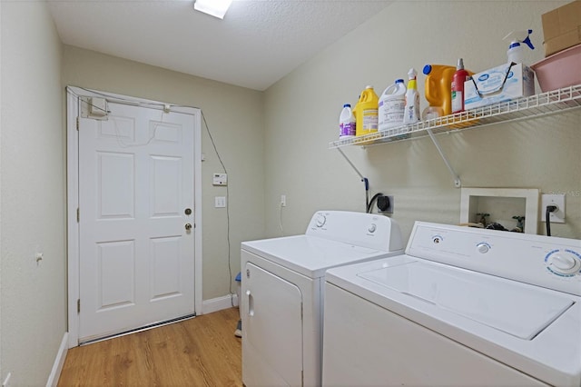 clothes washing area featuring baseboards, washer and clothes dryer, laundry area, light wood-style floors, and a textured ceiling