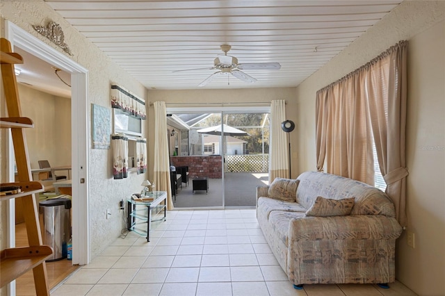 interior space featuring light tile patterned floors, a ceiling fan, and a textured wall