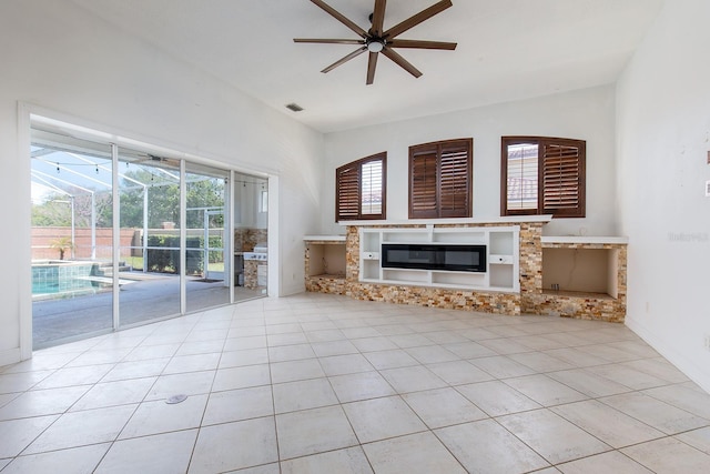 unfurnished living room featuring light tile patterned floors, visible vents, a ceiling fan, a glass covered fireplace, and a sunroom