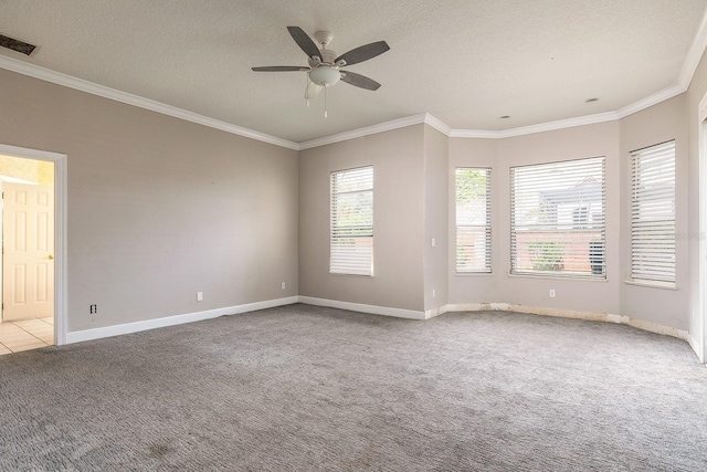 spare room with a textured ceiling, carpet floors, visible vents, baseboards, and ornamental molding