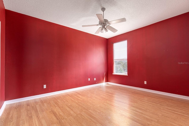 empty room featuring light wood-type flooring, ceiling fan, baseboards, and a textured ceiling