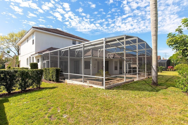 back of property featuring a lanai, a patio area, a lawn, and stucco siding