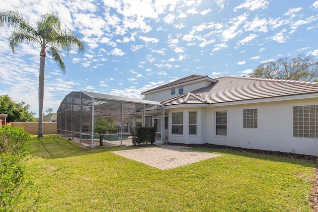 back of house featuring glass enclosure, a patio, a lawn, and stucco siding