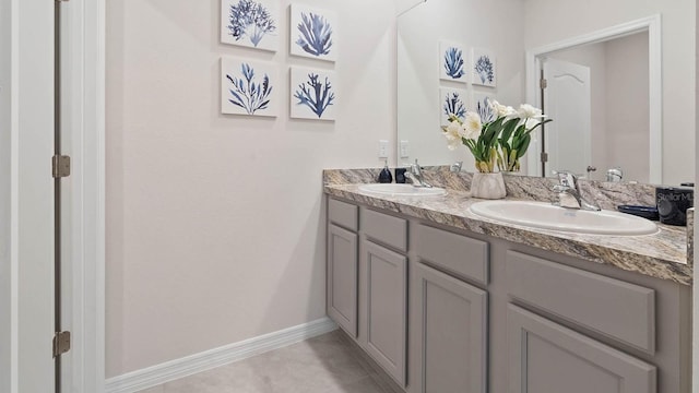 bathroom featuring double vanity, tile patterned floors, a sink, and baseboards