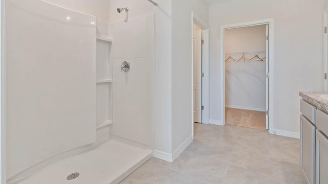 bathroom with a stall shower, a walk in closet, and vanity