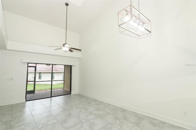 unfurnished room with a ceiling fan, a towering ceiling, baseboards, and light tile patterned floors