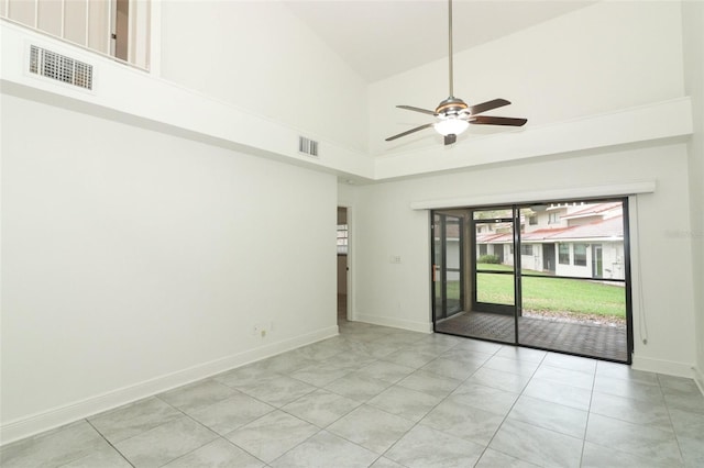 empty room featuring high vaulted ceiling, visible vents, baseboards, and light tile patterned floors