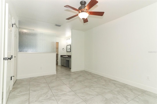 spare room featuring a ceiling fan, visible vents, and baseboards