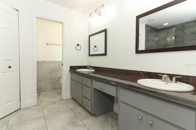 full bathroom with a sink, double vanity, a tile shower, and toilet