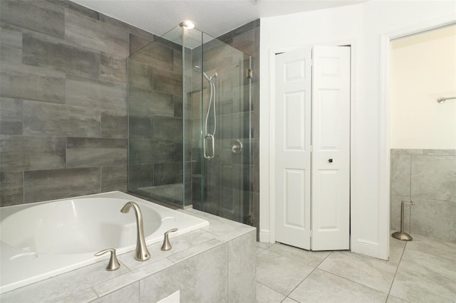 bathroom featuring a garden tub, a shower stall, tile patterned flooring, and tile walls