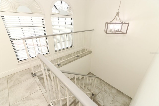 stairs featuring baseboards, tile patterned flooring, and a notable chandelier