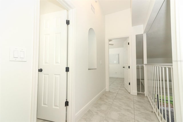 hall featuring baseboards and light tile patterned floors