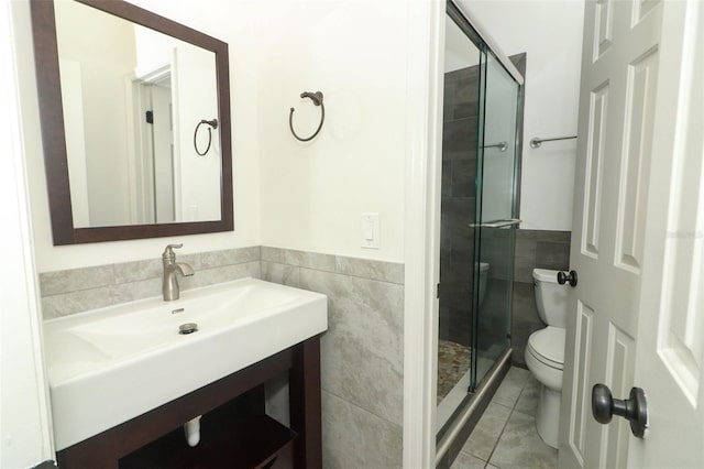 bathroom with a shower stall, tile patterned flooring, toilet, and tile walls