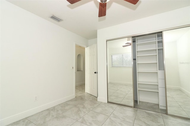 unfurnished bedroom with arched walkways, a ceiling fan, visible vents, and baseboards