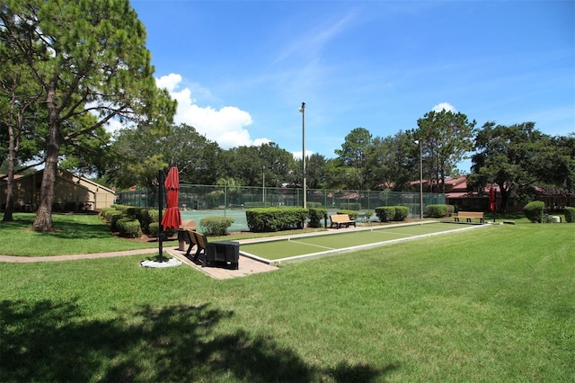 view of home's community with fence and a lawn