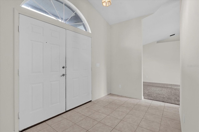 foyer featuring light tile patterned floors, baseboards, light carpet, and vaulted ceiling