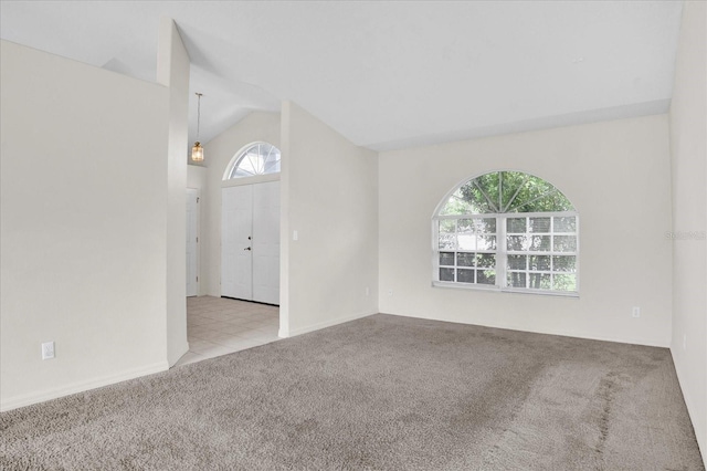 carpeted empty room with vaulted ceiling