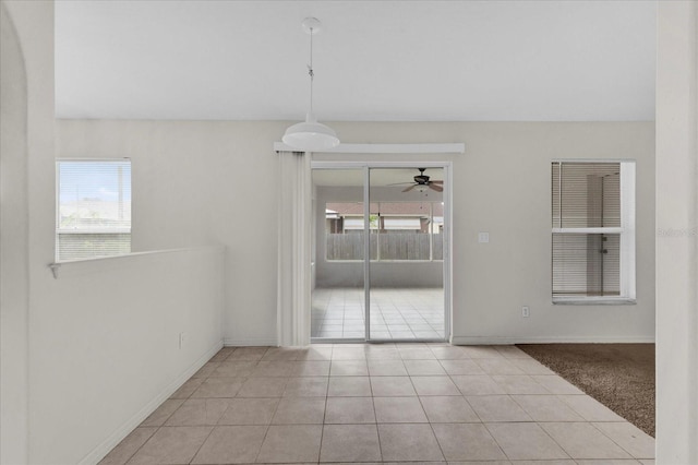 spare room with light tile patterned flooring, a healthy amount of sunlight, light carpet, and a ceiling fan