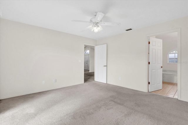 interior space featuring tile patterned flooring, carpet, ensuite bathroom, and ceiling fan