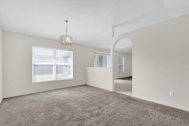 spare room with an inviting chandelier, carpet, arched walkways, and baseboards