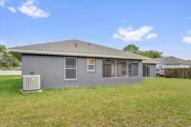 back of house featuring stucco siding, a lawn, central AC, and roof with shingles