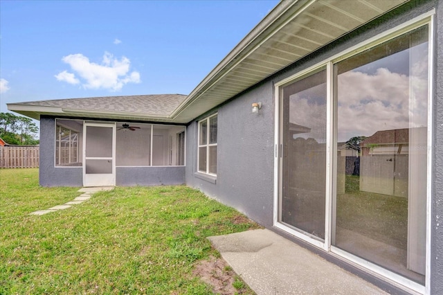 exterior space with stucco siding, a lawn, roof with shingles, and fence