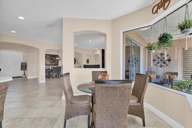 tiled dining room featuring arched walkways, baseboards, and recessed lighting