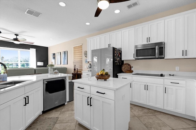 kitchen with stainless steel appliances, visible vents, a sink, and white cabinetry