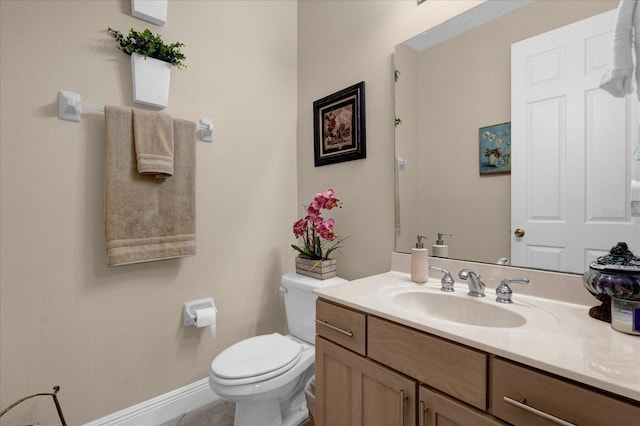 bathroom with toilet, baseboards, and vanity