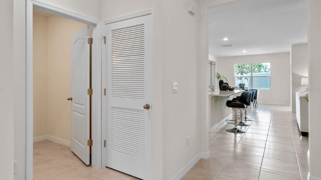 hallway featuring light tile patterned floors, recessed lighting, and baseboards