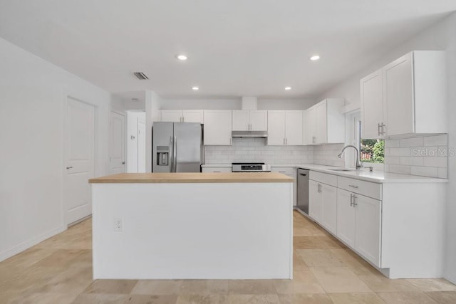 kitchen with visible vents, appliances with stainless steel finishes, white cabinets, a sink, and under cabinet range hood