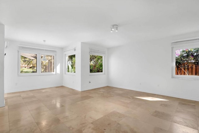 empty room featuring a healthy amount of sunlight and baseboards