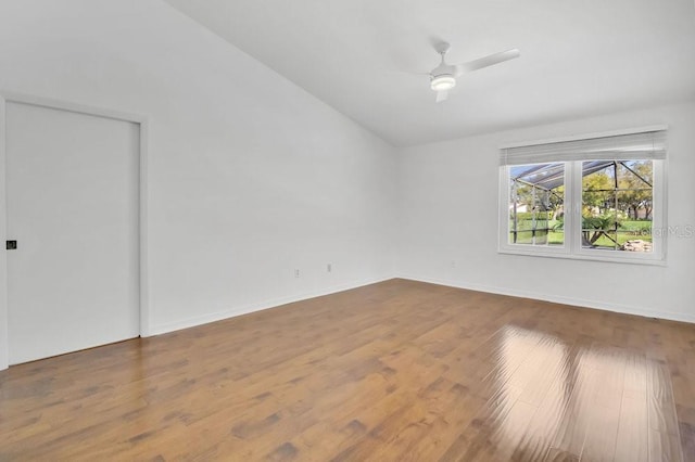 unfurnished room with vaulted ceiling, wood finished floors, a ceiling fan, and baseboards