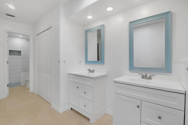 bathroom featuring a sink, visible vents, toilet, and two vanities