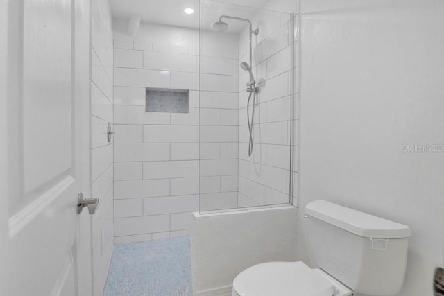 full bathroom with tiled shower and toilet