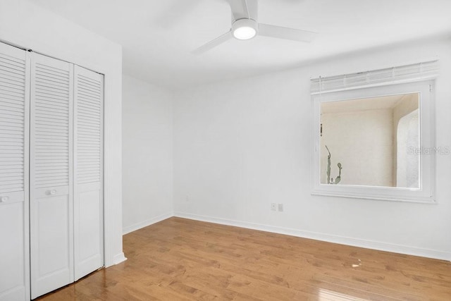 unfurnished bedroom with a ceiling fan, a closet, baseboards, and wood finished floors