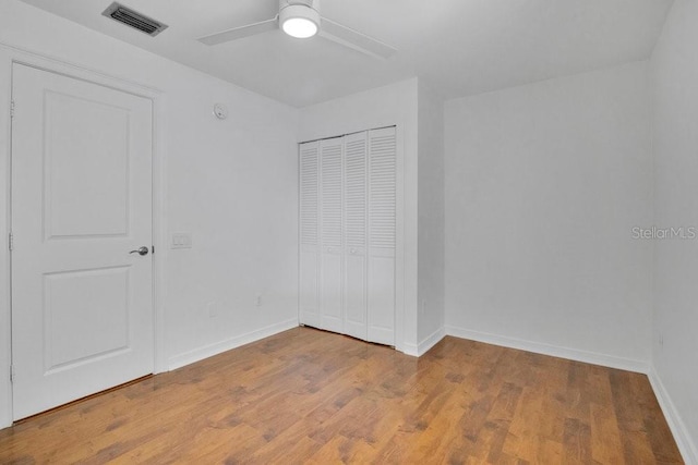 unfurnished bedroom with a closet, visible vents, baseboards, and wood finished floors