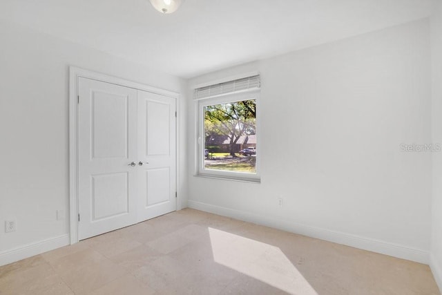 unfurnished bedroom with a closet and baseboards