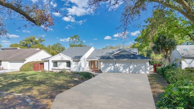 ranch-style house featuring an attached garage, fence, concrete driveway, and a front yard