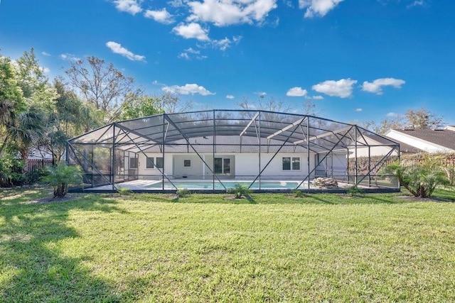 rear view of house featuring glass enclosure, a yard, and an outdoor pool