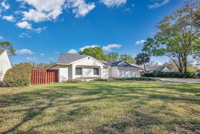 view of front facade featuring an attached garage, fence, a front lawn, and stucco siding