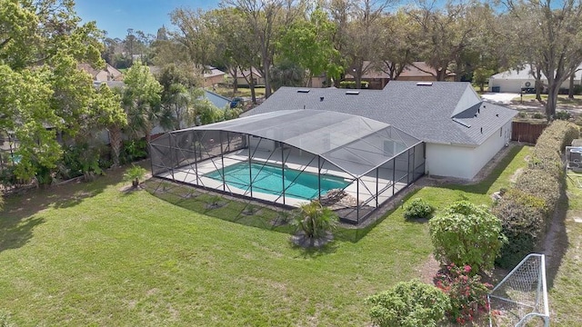 outdoor pool with glass enclosure, a lawn, and a patio