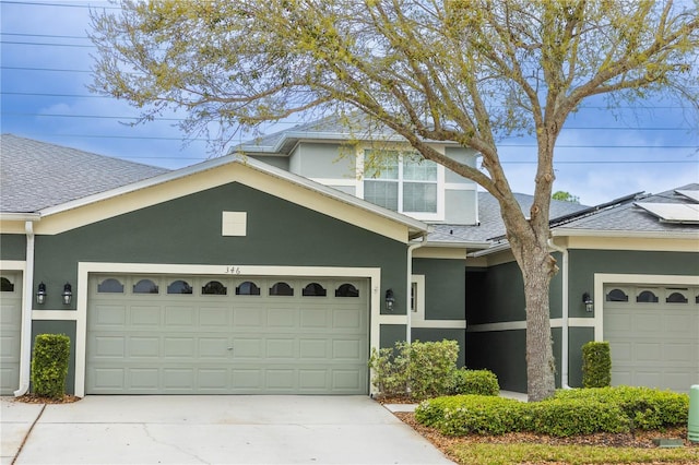 view of front of property with stucco siding, a garage, roof with shingles, and driveway