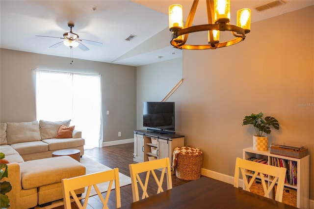 living room with dark wood-style floors, ceiling fan with notable chandelier, visible vents, and baseboards