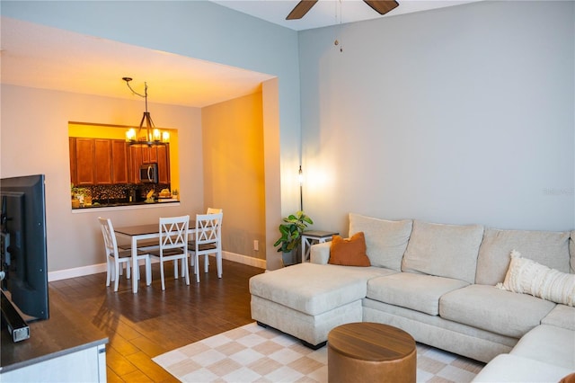 living area with ceiling fan with notable chandelier, baseboards, and wood finished floors